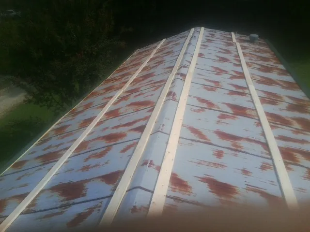 Rusted metal roof panels with new wood purlins before replacement — Storm Damage Roof Repair in Schofield by Roofing Brothers