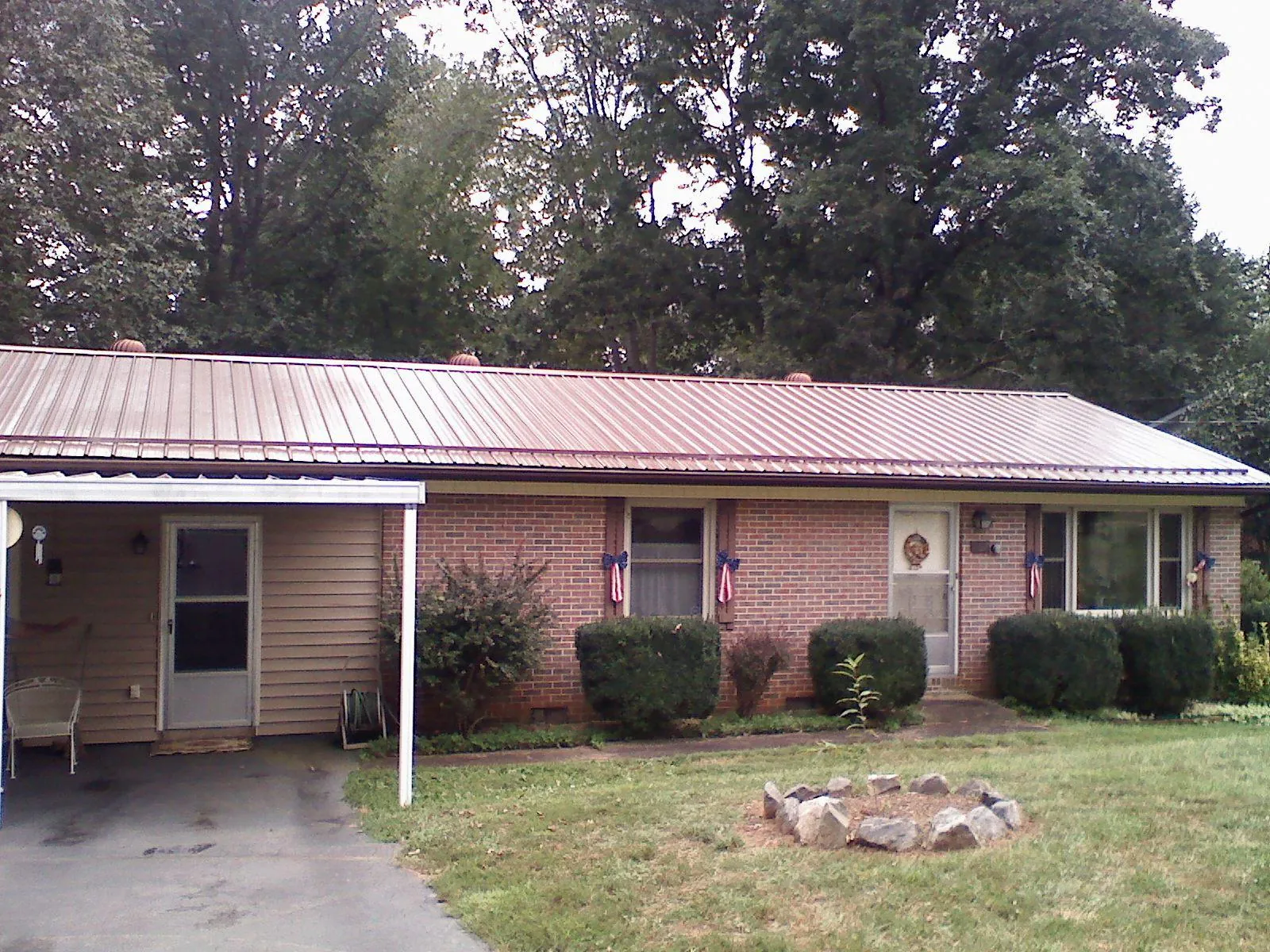 Bronze metal roof and carport on a brick ranch home — Roof Repair work by our crew in Schofield